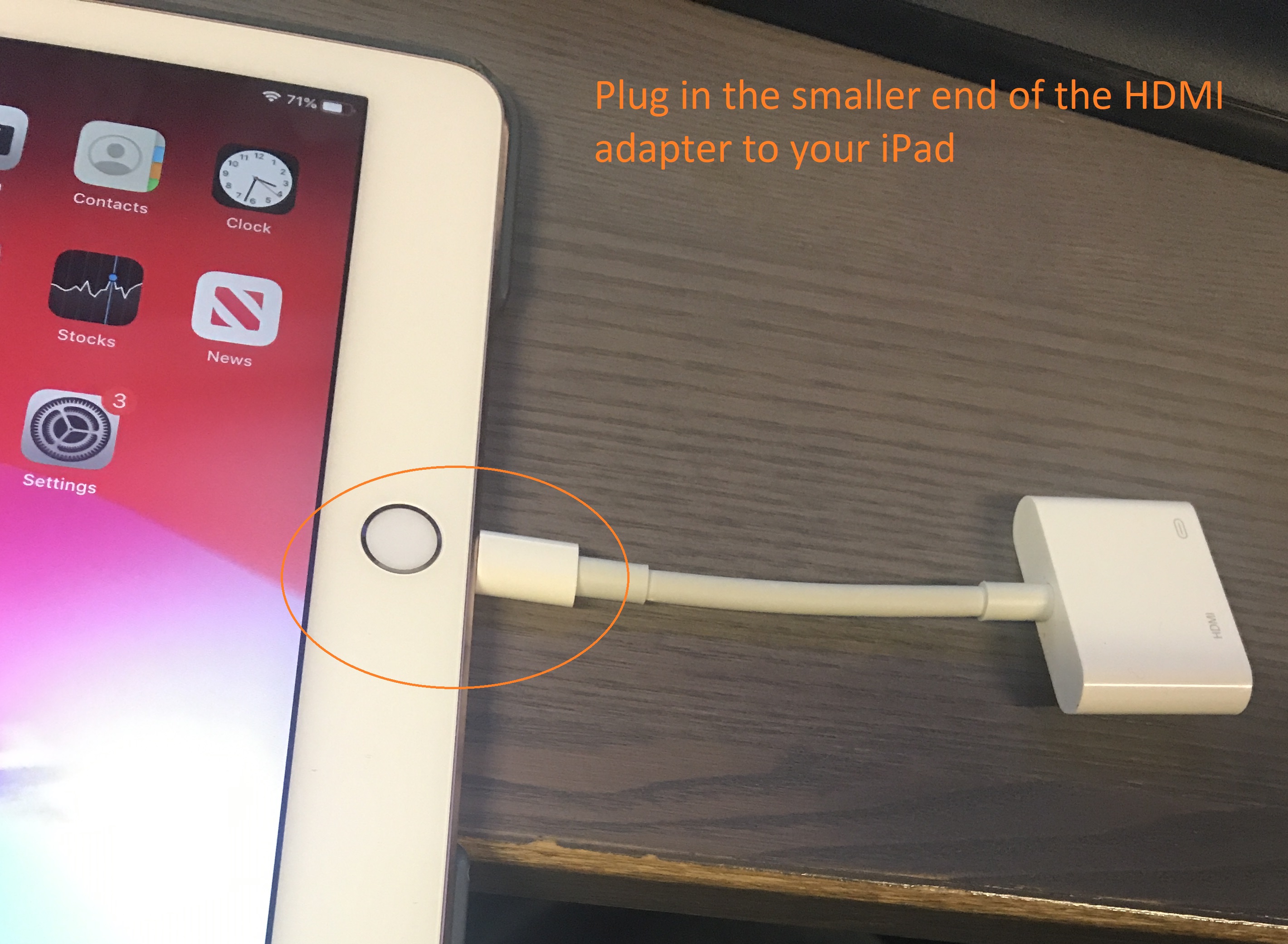 Adapter has a small rectangular plug at one end, large rectangle at the other. Small end plugged into iPad at center bottom.
